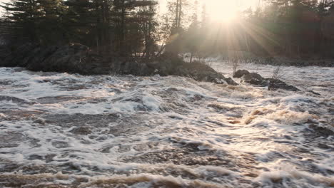 Los-Rayos-De-Sol-Arrojan-Un-Cálido-Resplandor-Sobre-Un-Río-Rugiente-Lleno-De-Nieve-Derretida-Primaveral.