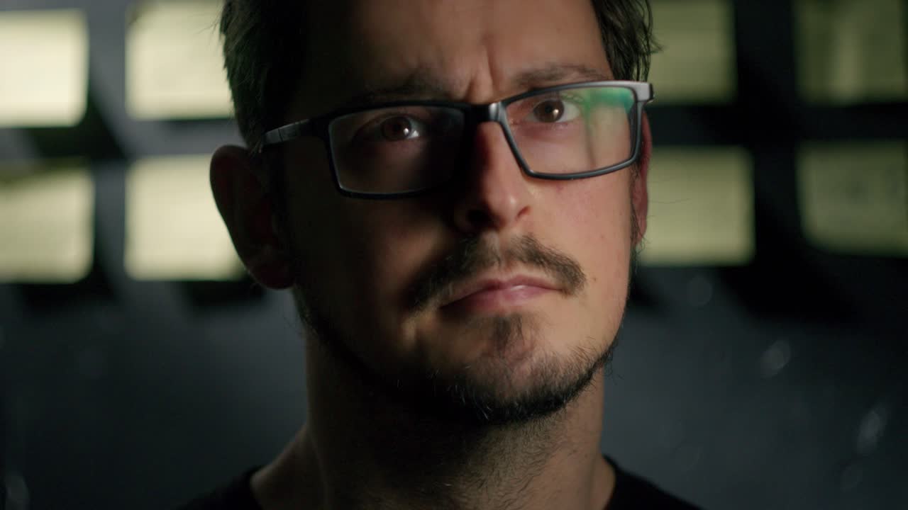 Man Standing Looking focused into the camera with Adhesive Board Notes In Office on the background closeup zoom out