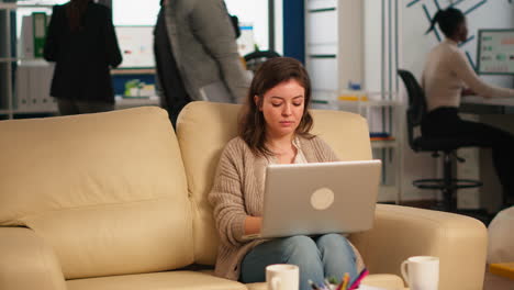 Young-woman-entrepreneur-sitting-on-couch-looking-at-camera