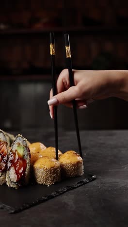 woman eating sushi with chopsticks