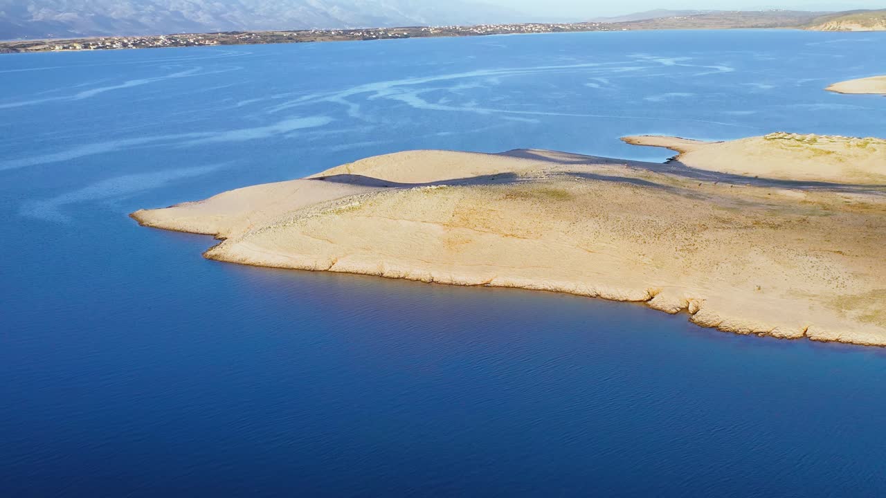 Aerial flying over arid hills in the island of Pag and Croatian mainland on background