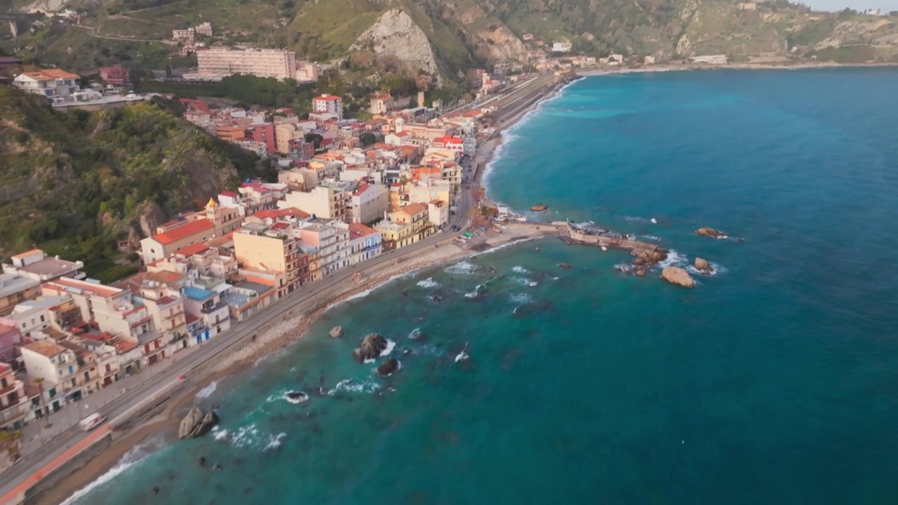 Volo aereo su Giardini Naxos Taormina: strada costiera, lungomare, spiaggia in Sicilia, paesaggio marino.