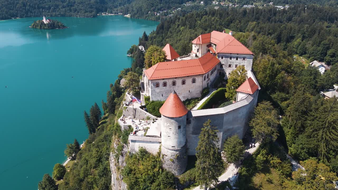 Drone view of Lake Bled castle in Slovenia with blue water of Lake Bled and forest around.