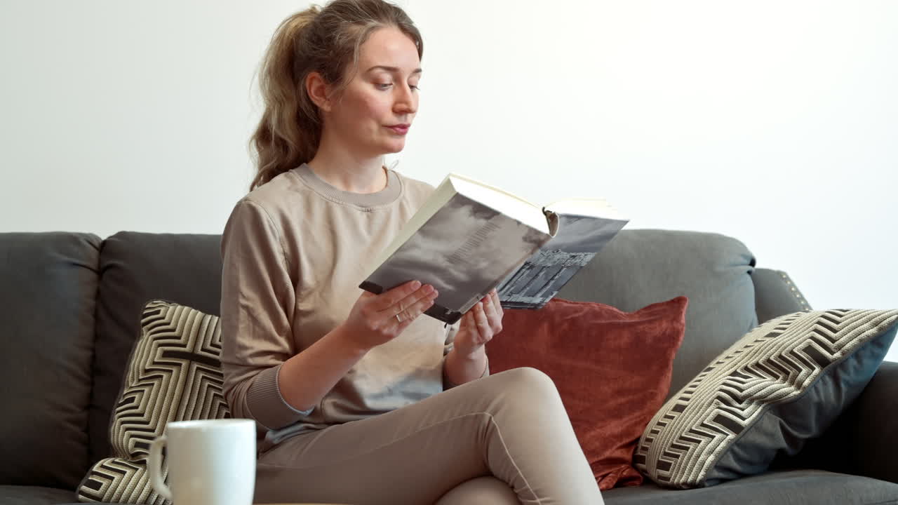 Woman reading a book at on the couch at home