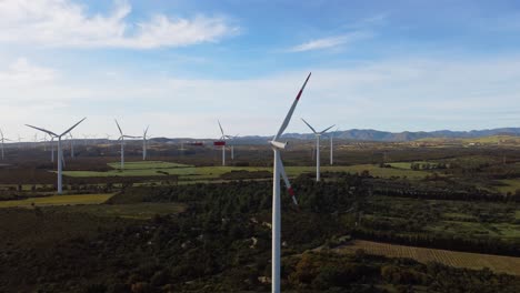 4k-aerial-view-of-wind-farm,-turbines-blades-spinning-in-rural-landscape