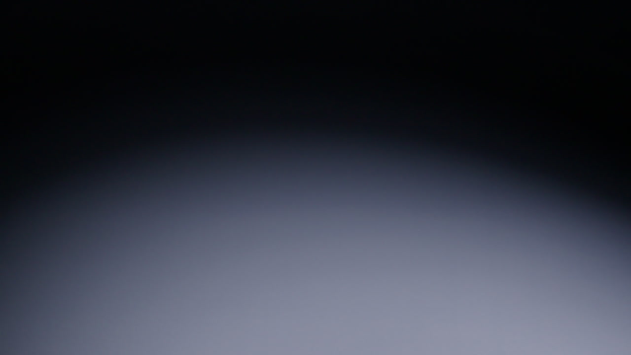 Slow-motion wide shot of red die rolling from screen right and out of shot on screen left