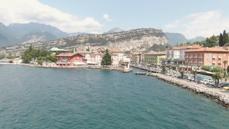 Aerial-view-of-lake-promenade-in-Torbole-on-Lake-Garda-with-cars-on-the-road-on-the-lake-on-a-sunny-day