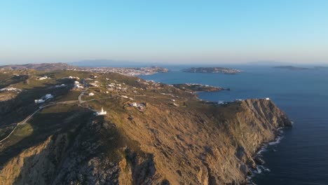 cinematic panoramic drone orbit of akrotiri in mykonos, showcasing the iconic armenistis lighthouse with chora village beautifully framed in the background against the sea and sky