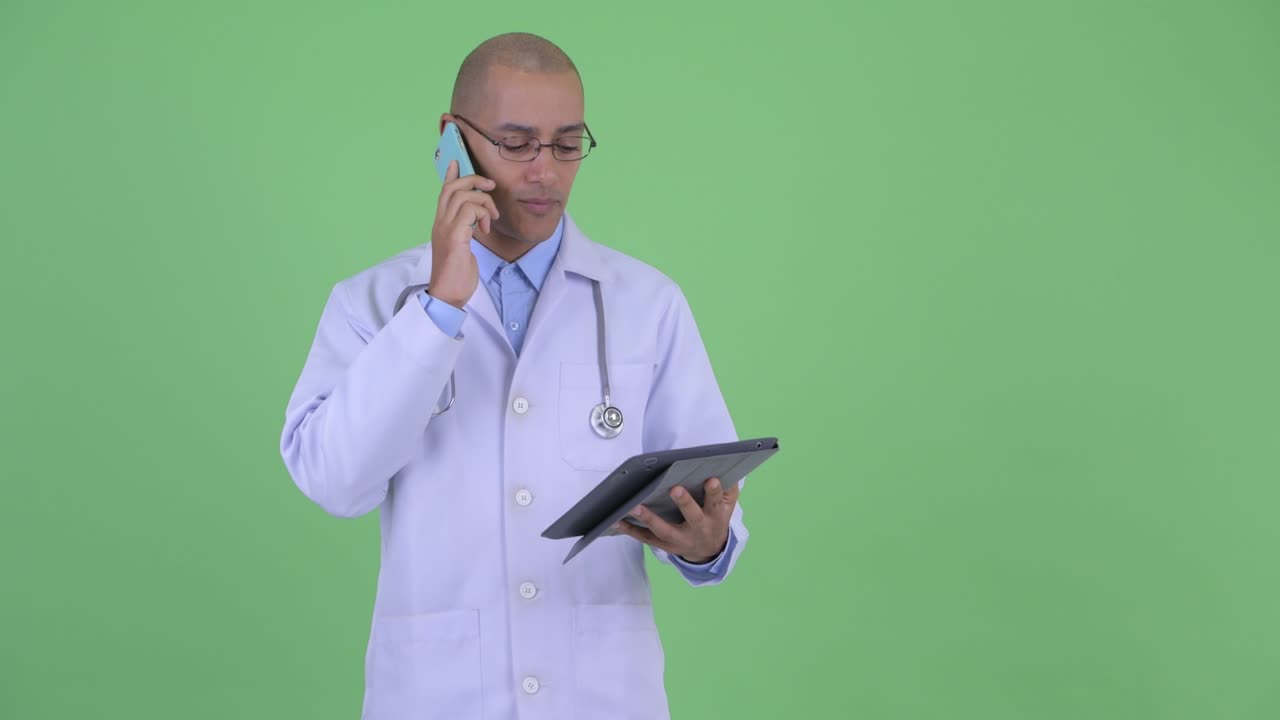 Happy bald multi ethnic man doctor using digital tablet