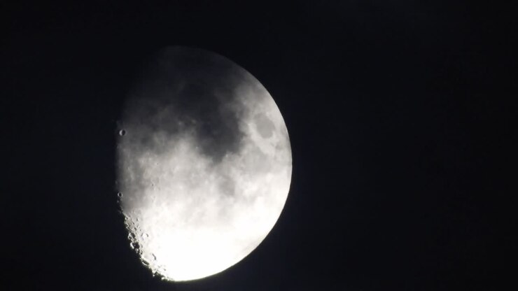 Moon at night with cloud real time. 4k video moon in the black sky. Clouds passing by moon at night. night sky with cloudy weather