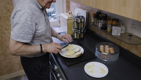 elderly man making sandwiches in kitchen