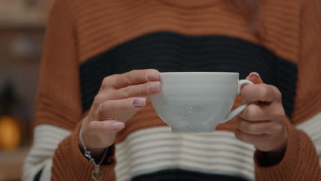 close up of tea cup held by young woman at home