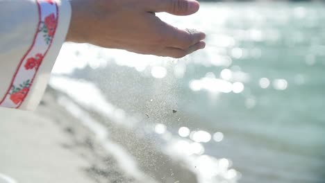 sand falling through hands by a river