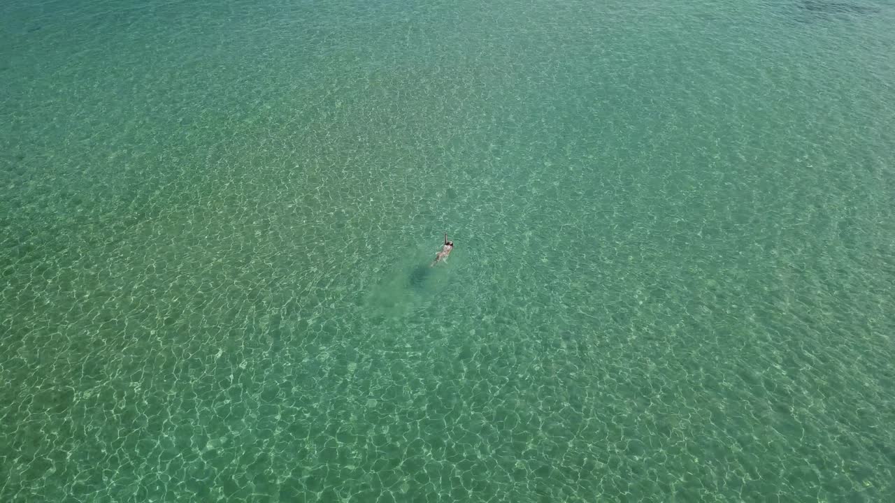 una turista nada en las cristalinas aguas verdes del mar egeo.
