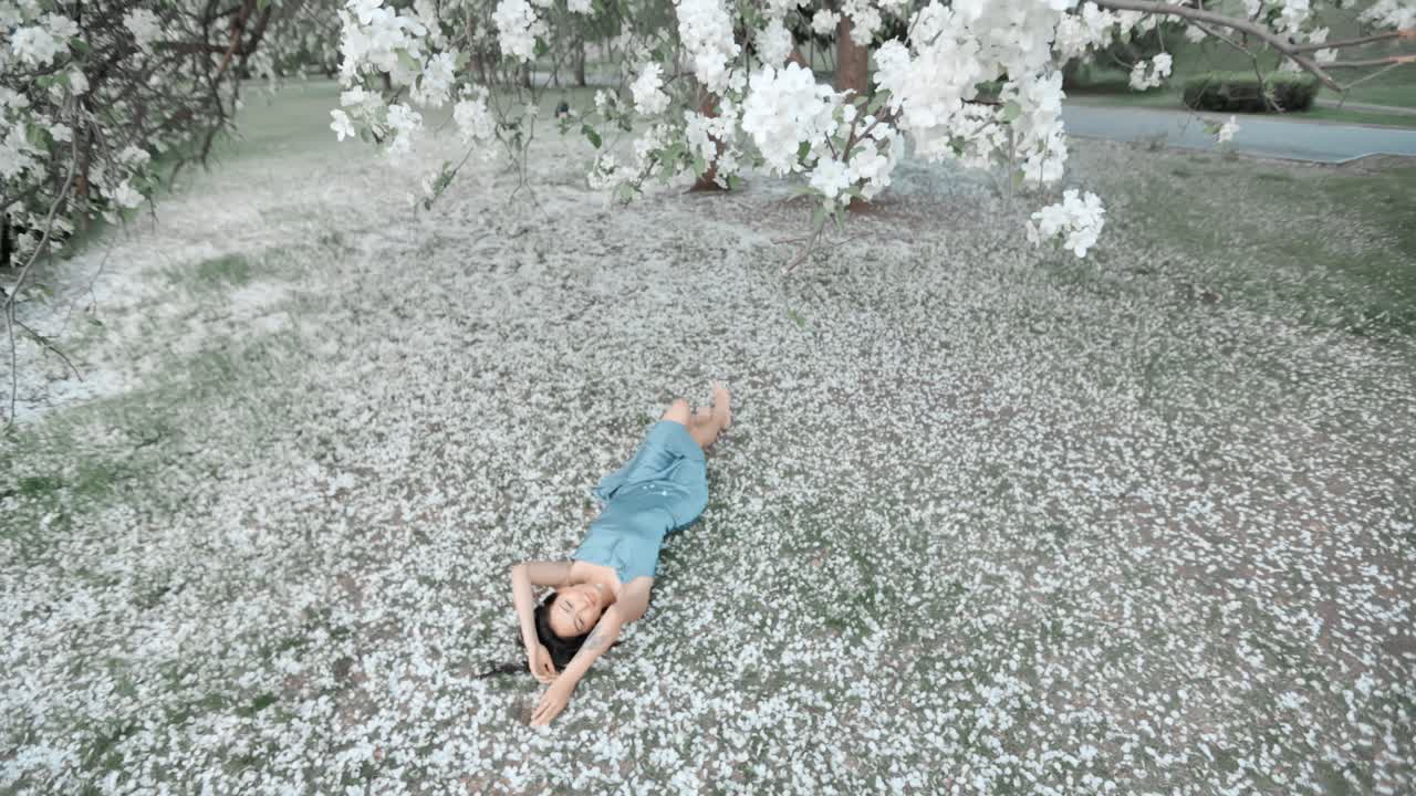 Woman Relaxing Under a Blossom Tree in a Park