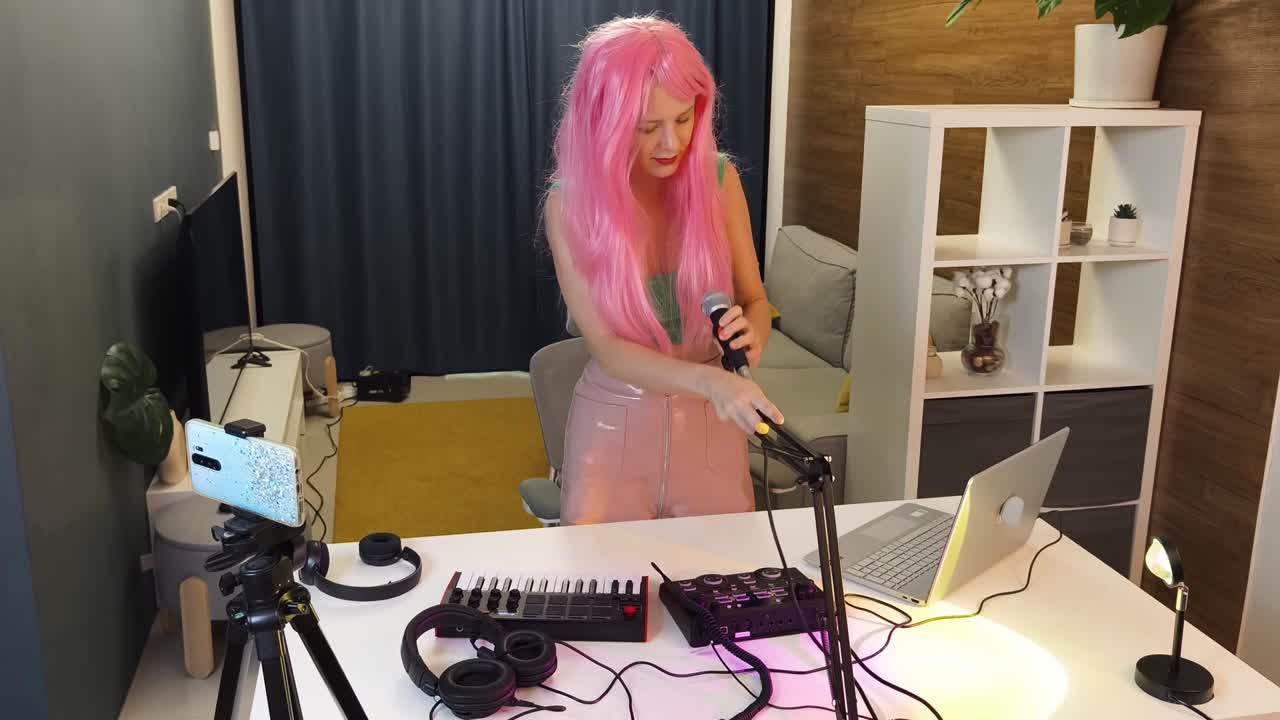 mujer de cabello rosa transmitiendo o grabando música en un estudio casero