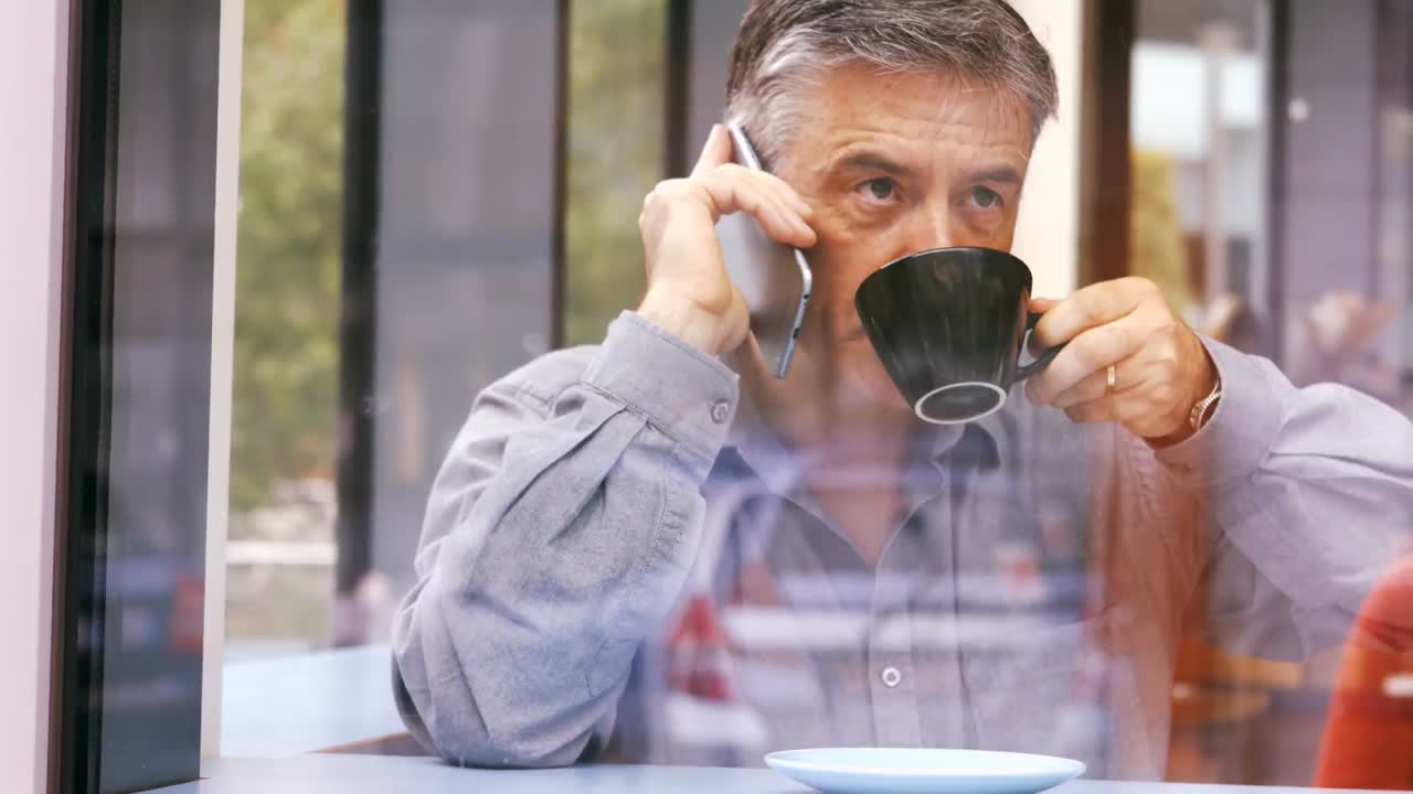 hombre de negocios hablando por teléfono móvil mientras toma una taza de café
