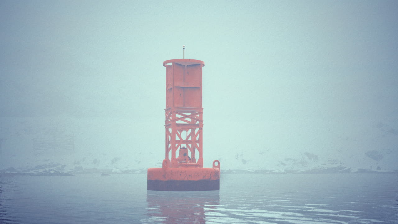 Bright orange buoy stands out in a foggy waterfront setting near a shoreline