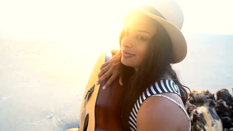 indian american girl with guitar on sunset beach