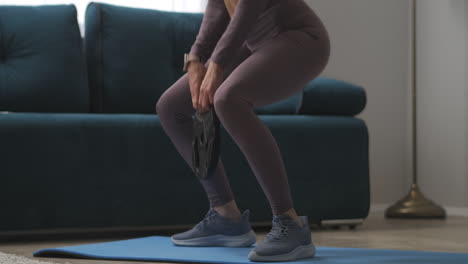 piernas delgadas de una deportista entrenando en casa haciendo sentadillas con peso en las manos bienestar y pérdida de peso aptitud para el fin de semana estilo de vida deportivo y saludable detalles de las partes del cuerpo