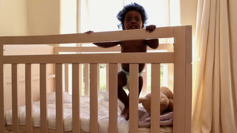 cute baby girl standing in her crib looking at camera