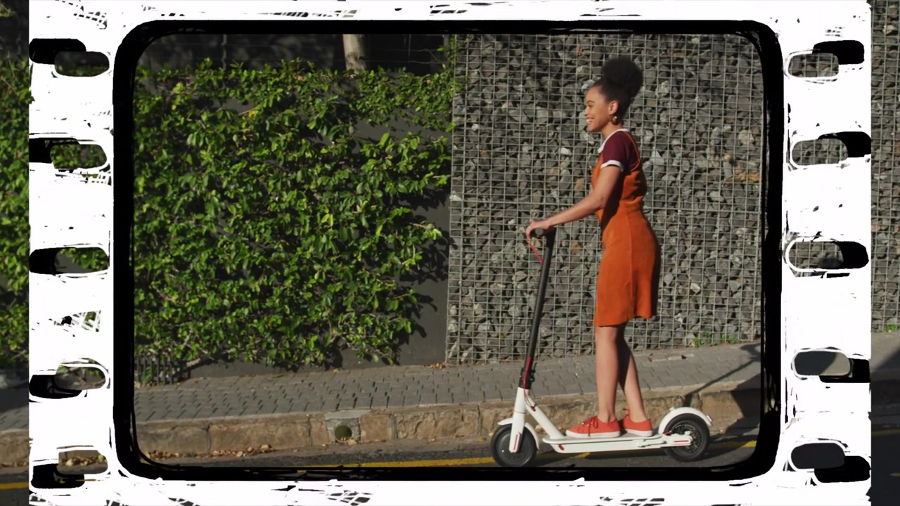 Scooter wheel appearing from right, woman riding electric scooter demonstrating urban mobility
