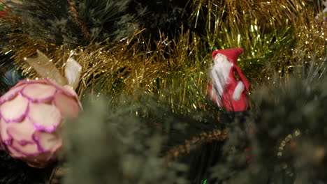 Hand-made-Santa-decoration-perched-on-a-Christmas-tree-with-baubles-and-tinsel