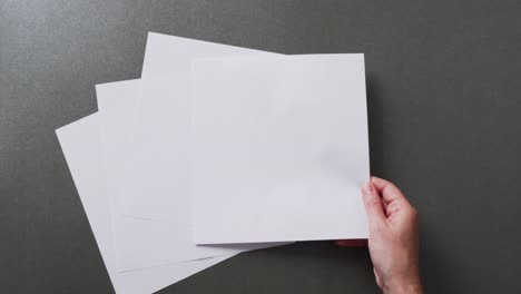 mano sosteniendo un pedazo de papel sobre pedazos de papel con espacio de copia en fondo gris en cámara lenta