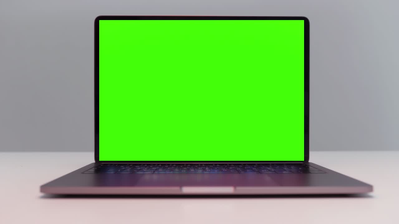 acercamiento de una nueva computadora portátil con monitor de clave chroma. acción. portátil abierto con pantalla verde aislada en fondo de pared blanca.