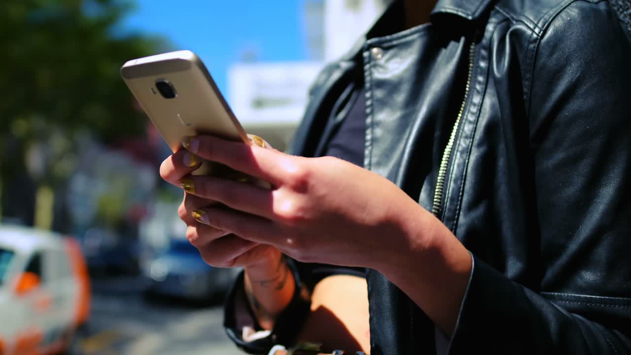 mujer de cabello rosa usando teléfono móvil en el callejón 4k