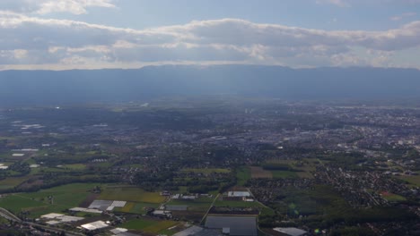 Lapso-De-Tiempo-Del-Valle-De-Ginebra-Con-Nubes-Y-Rayos-De-Sol-Brillando-Sobre-La-Ciudad,-Aún-Disparado-Desde-Las-Alturas-De-La-Montaña-Salève