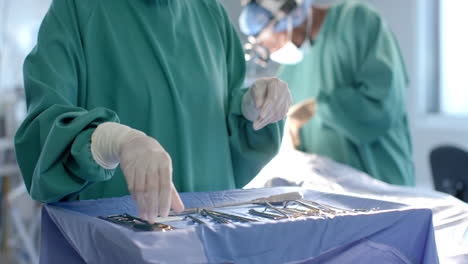 Midsection-of-female-surgeon-preparing-surgical-instruments-in-theatre,-copy-space,-slow-motion