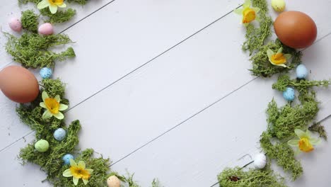 Colorful-decorative-Easter-eggs-wreath-on-white-wooden-table-background