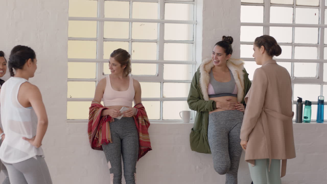 요가 수업 에서 건강 한 여성 들 이 대화 를 즐기고 생활 방식 을 공유 하고 피트니스 연습 을 논의 하고 스튜디오 에서 채팅 하고 있다