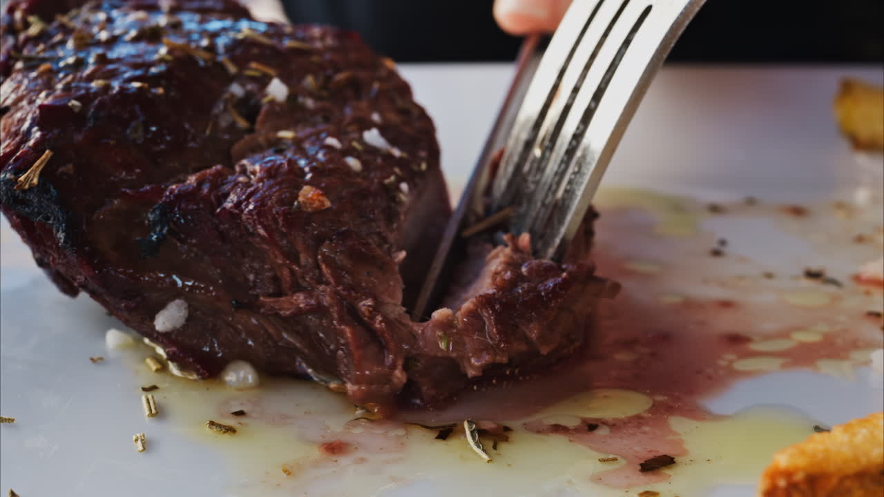 Close up of stake being cut near with fries and salad on a white plate