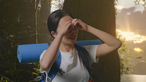de cerca de asiática mujer excursionista con mountaineering mochila haciendo binoculares gesto mirando algo y luego diciendo wow mientras explora la naturaleza del bosque