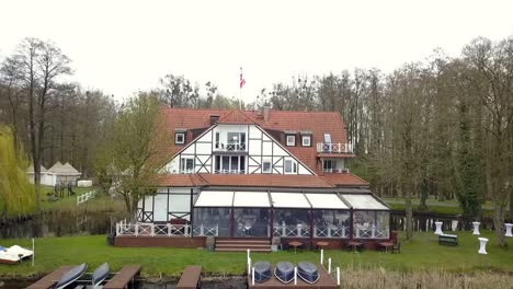 amazing aerial drone flight to a white half-timbered house by the lake at spring sunset on a lake at a perfect wedding location in brandenburg germany