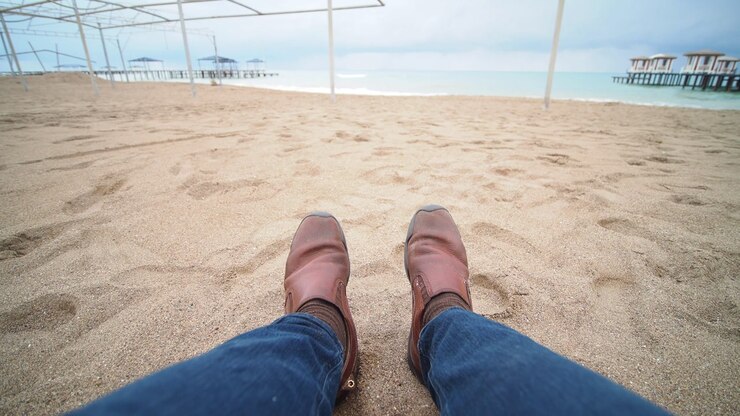 POV Shot of Legs and Feet Relaxing on a Sandy Beach by the Ocean