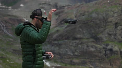 concentrated pilot takes off drone from hand, flying in majestic mountain landscape