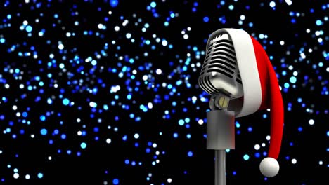 Santa-hat-over-retro-metallic-microphone-against-blue-spots-of-light-on-black-background