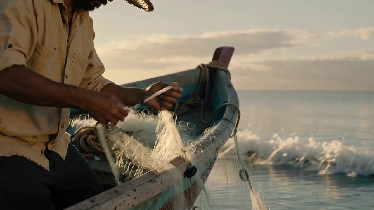 Pescador con sombrero de paja inclinado, inspeccionando y cuidando la red en un barco al atardecer, preparando el equipo, espacio para texto.