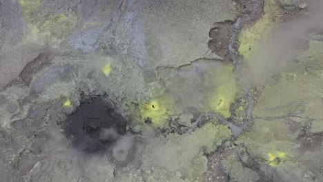 a drone shot of a mud geyser bubbling with yellow sulfur on top of mount garbuna in papua new guinea