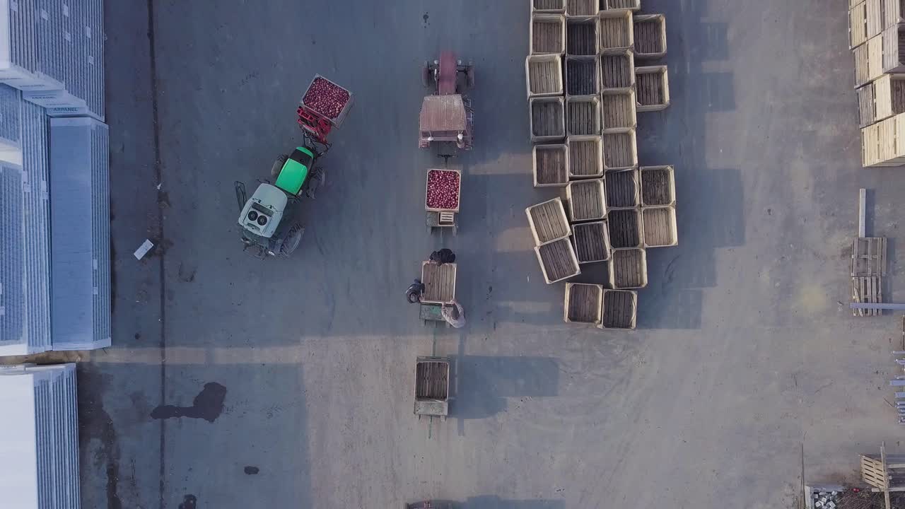 warehouse workers are preparing an empty crate for apples. Loader is relocating pallet with apples in the territory of warehouse for further transportation to the plant for the production of juice. Aerial view