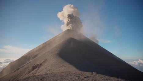 Erupting-Fuego-Volcano-in-Guatemala,-ash-clouds-against-blue-morning-sky