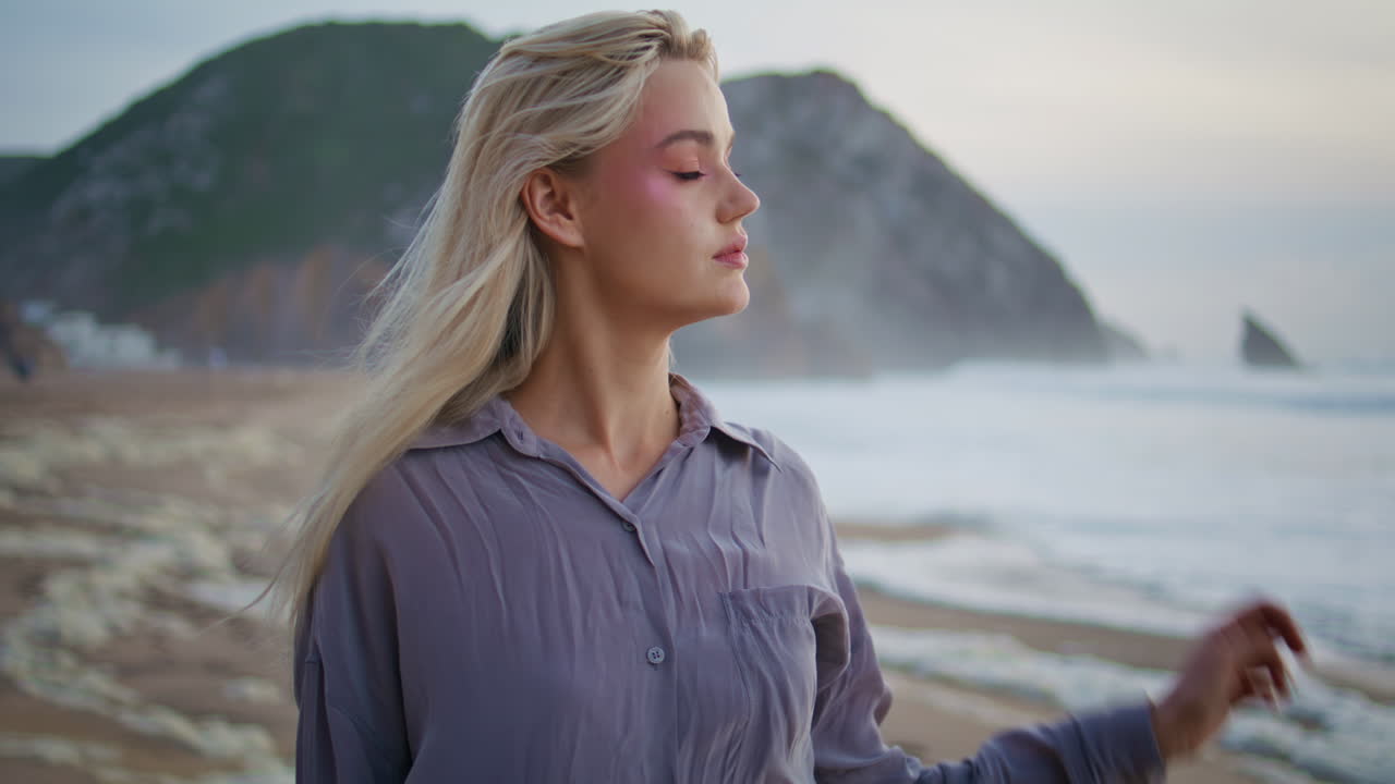 Viaggiatrice contemplativa che si riposa sulla riva dell'oceano, primo piano. Ragazza all'aperto che guarda la fotocamera.