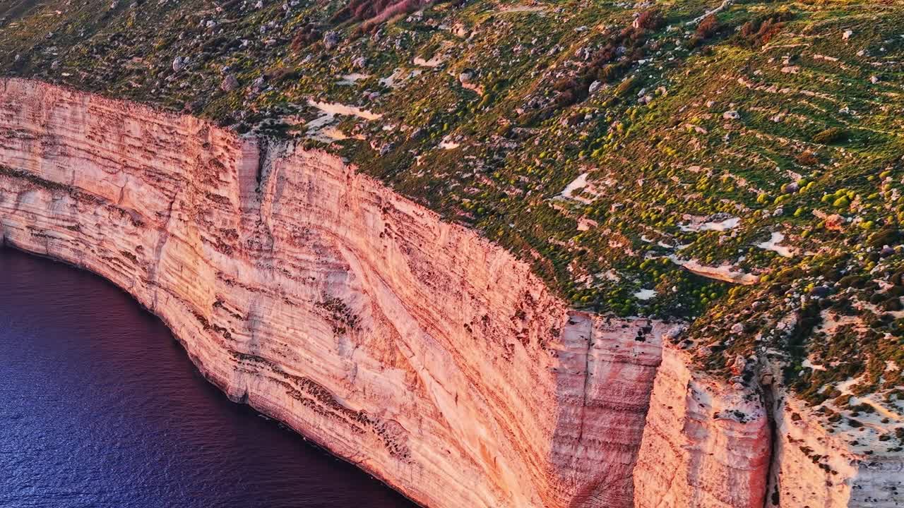 Cliffs and greenery overlook the sea in Malta during the late afternoon