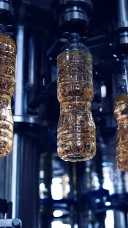 robotic equipment in the edible oil factory. modern industrial equipment pouring sunflower oil into the bottles moving on a circle production line. vertical video