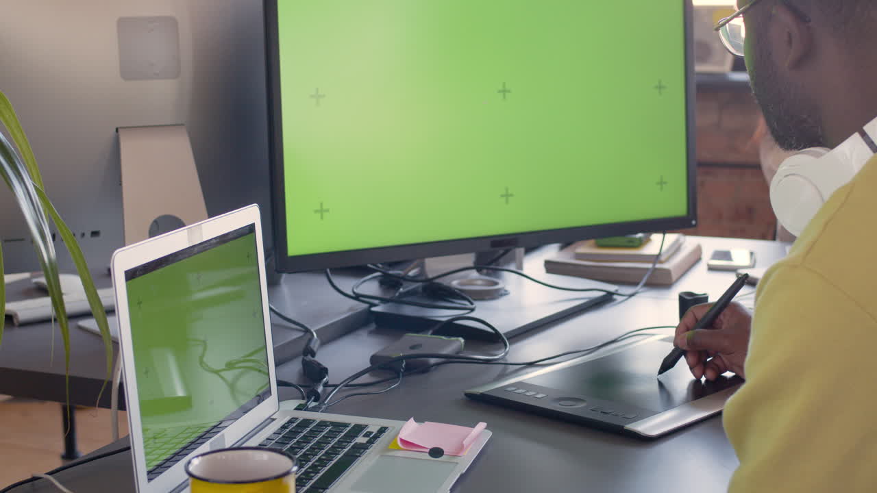 디지털 드로잉 태블릿을 사용하고 애니메이션 스튜디오에서 녹색 화면이 있는 모니터를 보는 그래픽 디자이너