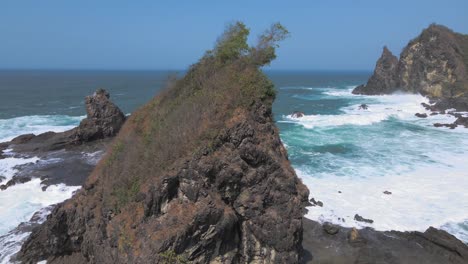 on the beach of watu lumbung in indonesia, waves crash white foaming on the coral rocks