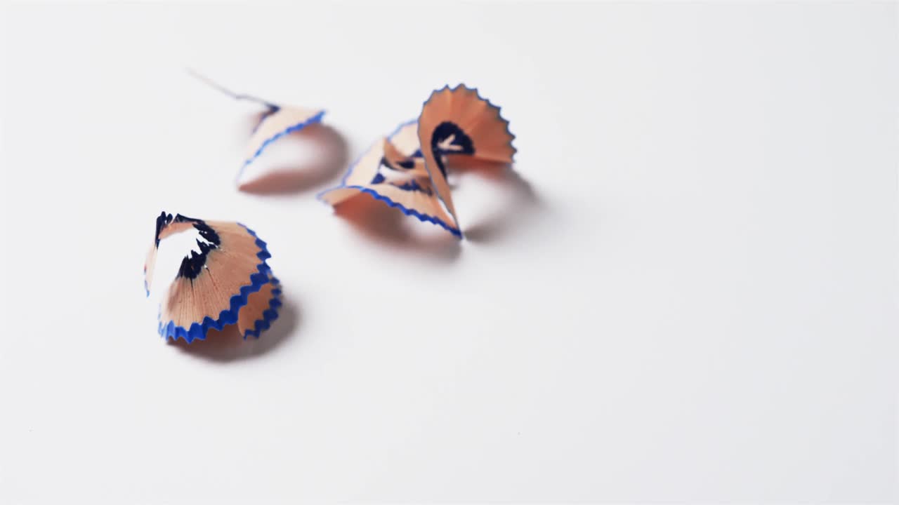 primer plano de virutas de lápiz azul con espacio de copia sobre fondo blanco, en cámara lenta